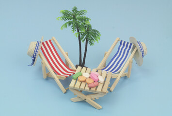 Empty blue and red beach chairs with hat and table with drugs on blue background. Medical tourism concept.