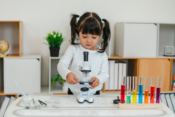 toddler girl scientist placing microscope slides with specimen. learning science
