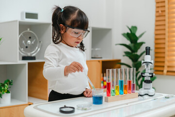 toddler girl scientist study using pipette dropping liquid with test tube and beaker. learning science