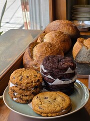 asorted chocolate chip cookies displayed in coffee shop, delicious assortment of freshly baked goods, natural light coming from a window on the left, 