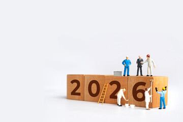 Transitioning from 2025 to 2026 with wooden blocks and miniature people. new year 2026 concept with white background.