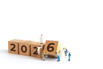 Transitioning from 2025 to 2026 with wooden blocks and miniature people. new year 2026 concept with white background.