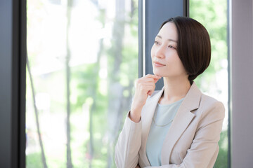 Fototapeta premium A businesswoman pondering by the window Wondering about her career, should she change jobs?