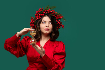 Woman in red dress with berry wreath holding hourglass, looking sideways