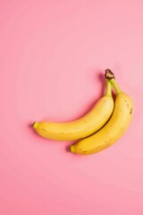 A vibrant duo of ripe bananas playfully arranged against a soft pink backdrop, creating a cheerful and appetizing visual