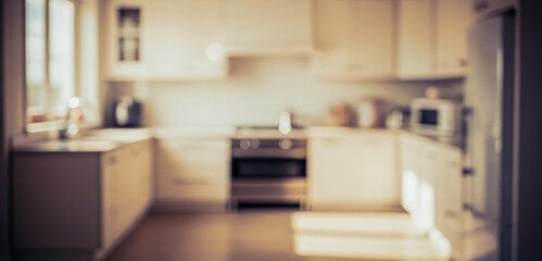 Blurred view of a kitchen with cabinets, oven, sink, and other appliances, creating a modern household setting with natural daylight and minimalistic decor.
