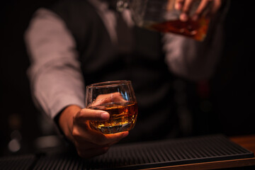 Bartender is pouring whiskey into a glass in a restaurant	