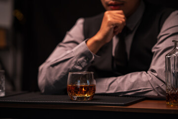 Business man bartender pours whiskey into a glass, sitting sadly in a restaurant	