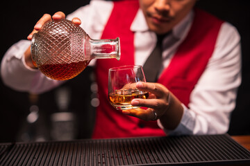 Bartender is pouring whiskey into a glass in a restaurant	