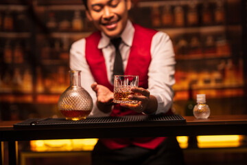 A bartender stands pouring whiskey for customers.
