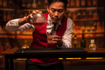 Bartender is pouring whiskey into a glass in a restaurant	