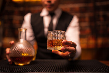 A bartender stands pouring whiskey for customers.
