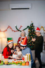 Joyful Asian family gathered for a Christmas feast, exchanging gifts, and celebrating the holiday season with love