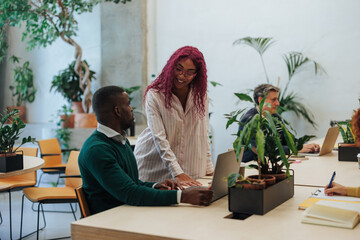 Colleagues collaborating on laptop in modern green office