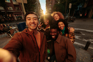 Obraz premium Group of happy multiracial friends taking photo of themselves at sunset in the city