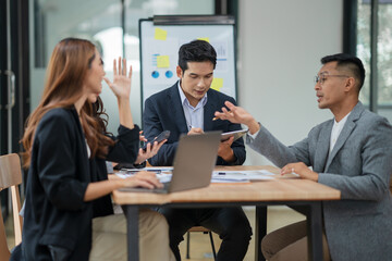 Group of Asian businesspeople sits down for a business investment planning meeting.	