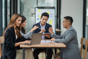 Group of Asian businesspeople sits down for a business investment planning meeting.	