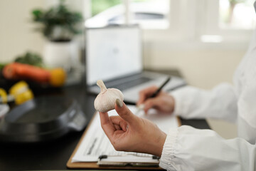 Fototapeta premium Healthcare professional, presumably a dietitian or nutritionist, with a clipboard in hand, writing notes in front of a table filled with various fresh vegetables