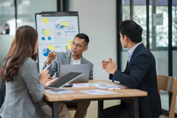 Group of Asian businesspeople sits down for a business investment planning meeting.	
