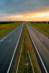 a colorful yellow sunrise over a highway with cars driving along it