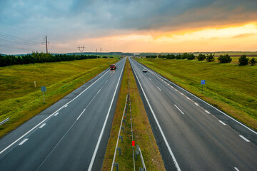 a colorful yellow sunrise over a highway with cars driving along it