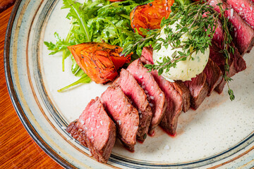Slices of perfectly grilled steak are accompanied by vibrant greens and tender roasted tomatoes
