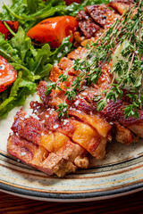 Juicy roasted pork crackling served alongside a colorful salad of fresh greens and cherry tomatoes