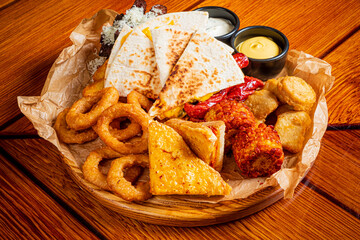 A tempting platter filled with crispy onion rings, quesadillas, and savory snacks awaits enjoyment