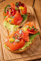 Freshly made avocado toast features smoked salmon, tomatoes, and greens, perfect for brunch