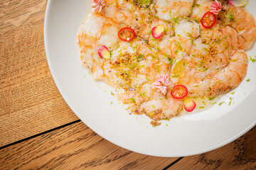 Shrimp ceviche topped with chili slices and edible flowers on a rustic table