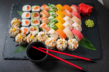 Vibrant sushi rolls with salmon, tuna, and crab rest on a slate with chopsticks nearby