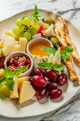 A vibrant cheese platter presents a variety of cheeses, fresh grapes, nuts, and mint leaves
