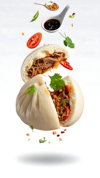Flying steamed bakpao with half bite open, condiments like vinegar and chili flakes apart. Perfect for food advertising, restaurant promotions, menu designs.