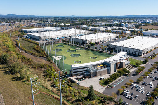 Hillsboro, OR, USA - Sep 22, 2025- High quality aerial drone picture of Topgolf Hillsboro entertainment and driving range facility with golf nets, parking lot and surrounding commercial area 