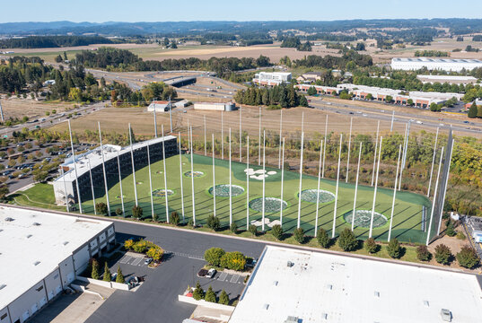Hillsboro, OR, USA - Sep 22, 2025- High quality aerial drone picture of Topgolf Hillsboro entertainment and driving range facility with golf nets, parking lot and surrounding commercial area 