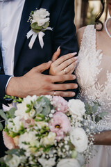 Bride and groom hugging on their wedding day and holding a bouquet of flowers