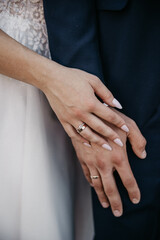 The groom and bride placed their palms on each other, showing off their manicured fingers and gold wedding rings on their wedding day