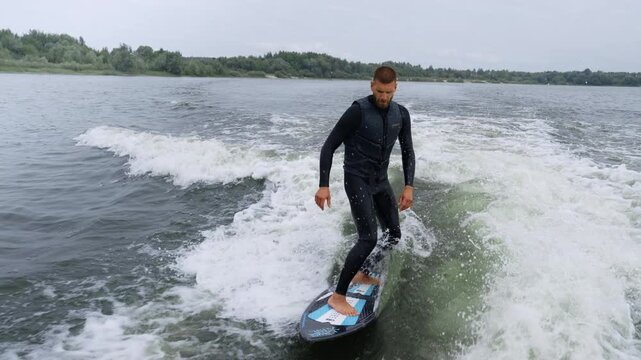 Surfer skillfully rides a wakeboard across the water with dynamic wave action unfolding