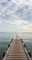 Obraz premium Serene scene featuring fishing rod on a wooden pier under a cloudy sky