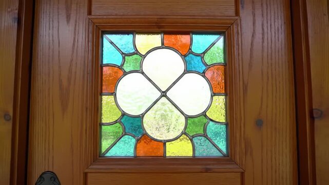 Close-up of a decorative stained glass panel with a cloverleaf design set within a wooden door frame