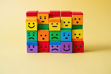 Colorful wooden blocks depicting diverse emotions on a soft yellow backdrop