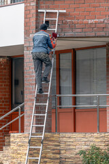 A man works on the facade from a ladder on an autumn day