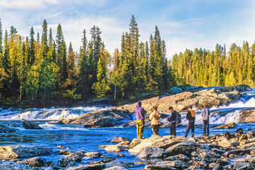Young boys by  a rapid river in a forest at autumn