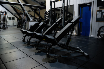 Three black exercise benches are lined up in a gym