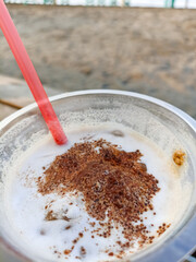Close-up view of cold coffee drink with latte art sprinkles in a plastic cup with abstract background