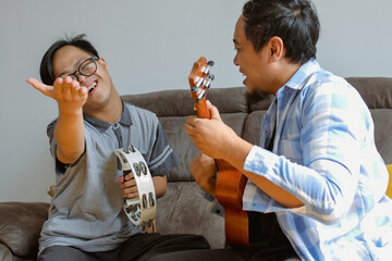 Father Playing Ukulele with His Special Needs Son in Living Room at Home