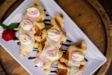 Delicious croissant pastry with chocolate drizzle, cookie crumbs, and vanilla ice cream served on a white plate with strawberry garnish.