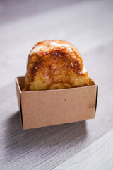 Freshly baked sweet bread roll with golden crust served in brown paper box, ideal for bakery promotion, food packaging design, or cafe menu showcase.