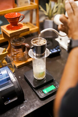 Barista preparing iced Vietnamese coffee with phin filter and condensed milk on digital scale.