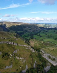 Obraz premium Aerial view of a lush green valley with rolling hills and a blue sky